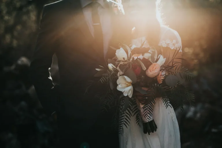 couple just married, woman holing bouquet of flowers. Sun setting